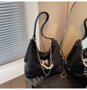 Détail du sac bandoulière en tissu noir avec boucle papillon et décoration de perles
