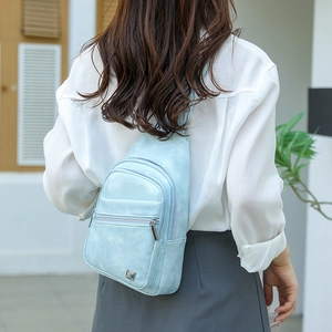 Close-up of a light blue multi-layer crossbody chest bag with metallic zipper details