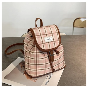Detail of pink plaid mini backpack with brown leather trim and lace logo on stone table