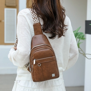 Detail of deep brown vintage leather chest bag featuring wide wave woven shoulder strap