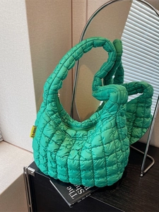 Quilted lime green cloud bag with puffy design and fashion tag on a mirrored surface