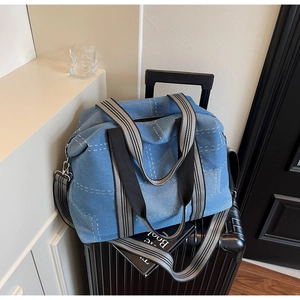 Close-up of denim tote bag with quilted stitching on a suitcase for travel use
