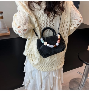 Détail du sac seau en velours noir avec poignée en perles de résine et bandoulière