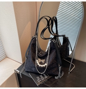 Détail du sac hobo à paillettes noires avec chaînes et breloque papillon