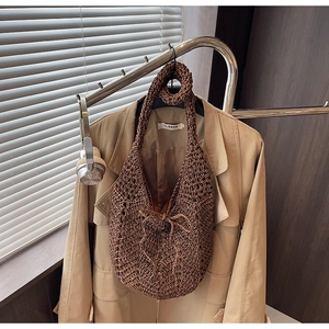 Detail of dark brown hollow-out knit tote bag with a woven bow on a khaki coat