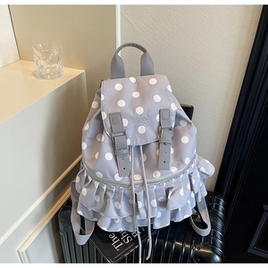 Detail of lavender polka dot backpack with ruffled layers on a black suitcase