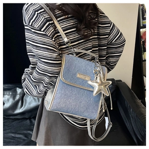Detail view of denim shoulder bag with silver metallic trim and star charm
