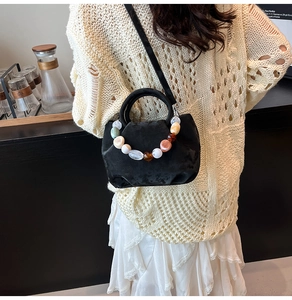 Détail du sac seau en velours noir avec des perles colorées et une bandoulière