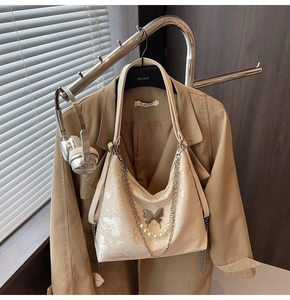Détail du sac hobo crème avec chaîne en perles et boucle papillon argentée brillante