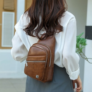 Close-up of brown PU leather crossbody bag with three silver zippers and textured finish