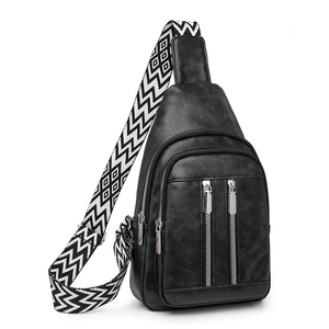 Detail of black PU leather chest bag with three zipper compartments and geometric strap