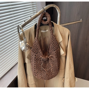 Detail of hollow crochet knit shoulder bag in dark brown with a central decorative bow