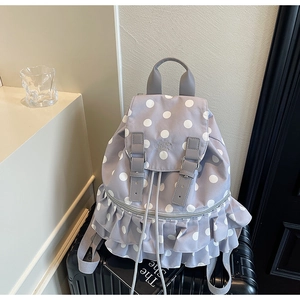Detail of gray polka dot backpack with ruffle trim on luggage for travel use