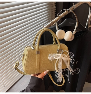 Detail of light green litchi leather pillow bag with pearl lace bow charm and strap