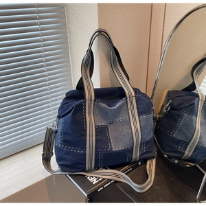 Detail of blue denim patchwork tote bag with contrast stitching and striped top handles