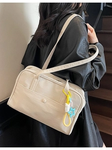 Grande borsa tote in tela beige con ciondolo a stella, indossata da modella su scale