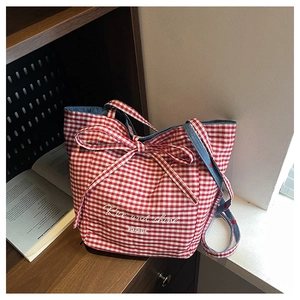 Detail of red checkered canvas tote bag with bow tie and blue denim strap