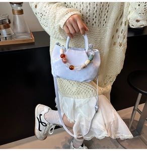 Détail d'un sac seau plissé violet clair avec une poignée en grosses perles colorées