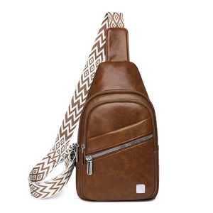 Detail of vintage brown PU leather sling bag with patterned wide woven strap