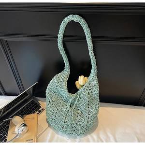Close-up of mint green hollow-out knit tote bag with delicate wave pattern texture