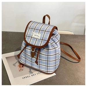 Detail of blue and white checkered canvas backpack with leather trim and drawstring closure