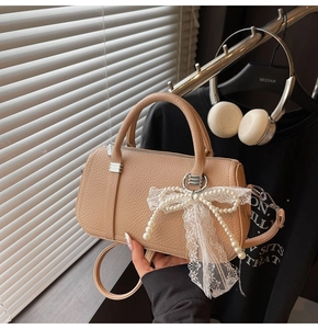 Detail of beige faux leather pillow bag featuring delicate lace bow and pearl decoration