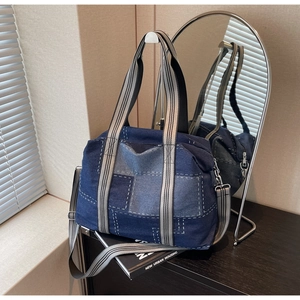 Detail of color-block denim tote bag with striped straps on wooden table