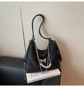 Détail du sac bandoulière en jacquard noir avec rivets argentés, perles et papillon