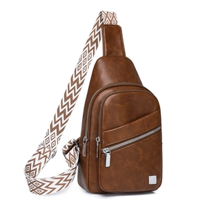 Detail of caramel brown faux leather chest bag with woven strap and metallic plaque