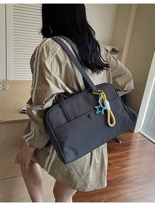 Borsa tote in tela grigio scuro minimalista con ciondolo a stella, indossata da modella
