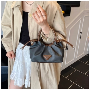 Detail of black nylon shoulder bag featuring brown leather handles and a triangle logo