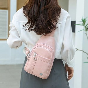 Close-up of pink PU leather chest bag with adjustable woven strap and metal logo detail