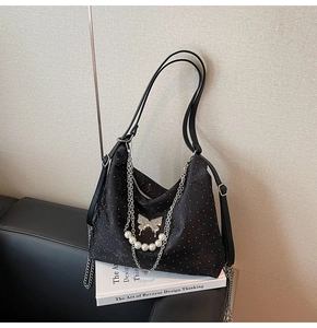 Détail du sac cabas en jacquard noir avec breloque papillon, perles et chaînes argentées