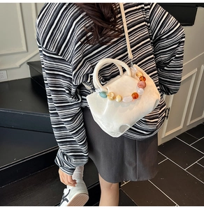 Sac seau plissé blanc avec poignée en perles de résine colorées sur un mannequin