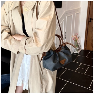 Detail of dark gray fabric tote with brown leather handles and drawstring closure