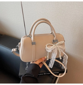 Detail of beige lychee leather bag with pearl lace bow charm and silver hardware