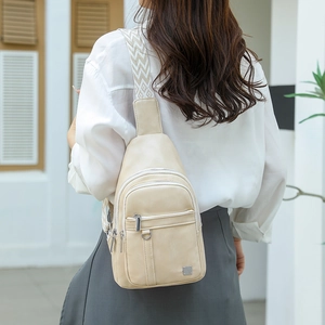 Detail of beige leather chest bag with geometric woven strap and multiple zipper pockets