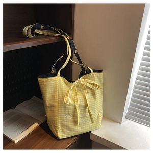 Detail of yellow plaid canvas tote with a bow and floral embroidered shoulder strap