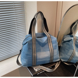 Macro shot of blue denim tote with striped webbing handles and metal hardware detail
