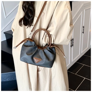Close-up of pleated shoulder bag with dark brown leather straps and metal triangle plaque