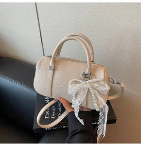 Detail of beige leather Boston bag featuring lace pearl bow and silver hardware