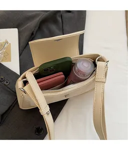 Top view of spacious interior of a beige leather crossbody bag with items inside