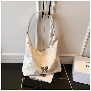 Detail einer cremefarbenen Hobo-Bag mit Blumenmuster und Metallschmetterlingsschließe