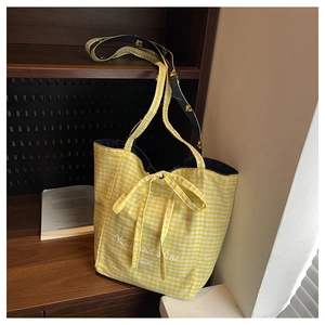 Detailed view of yellow plaid canvas tote bag with Rise and Shine print and bow decoration