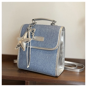 Detail of denim and silver leather bag with metallic star charm and logo plaque