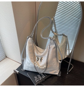 Détail d'un sac à dos en dentelle argentée avec fermoir papillon et chaînes de perles