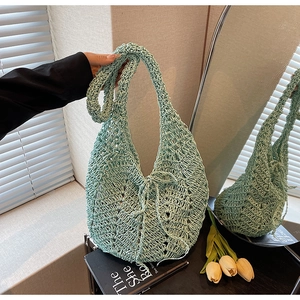 Close-up of light green crochet knit tote bag with hollow pattern and drawstring bow detail