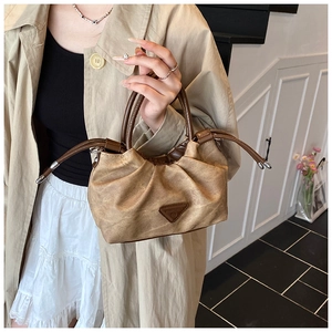 Detail of vintage pleated brown shoulder bag with double handles and side drawstring accent