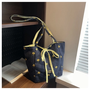Detail of denim tote bag with yellow flower embroidery and plaid ribbon handle decoration