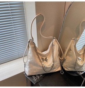 Détail du sac hobo crème avec motif papillon jacquard, chaîne de perles et boucle métal